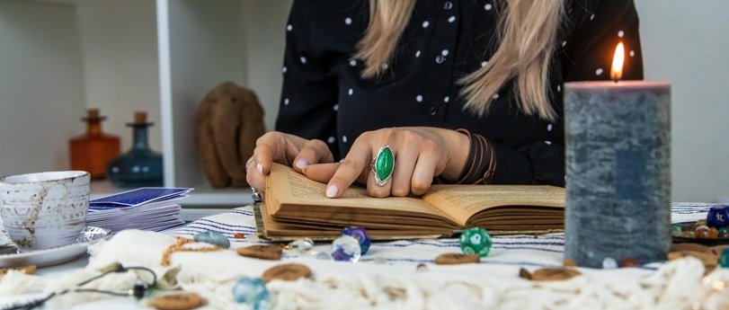 Woman fortune teller reads a book of spells. Selective focus. People.