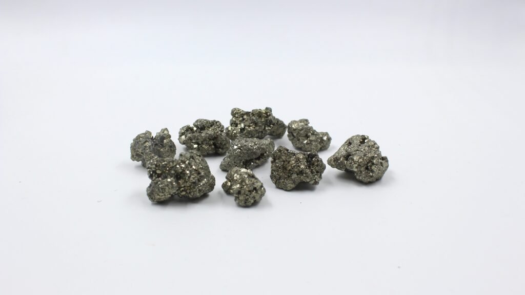 A group of pyrite nuggets, also known as fool's gold, displayed on a white surface.