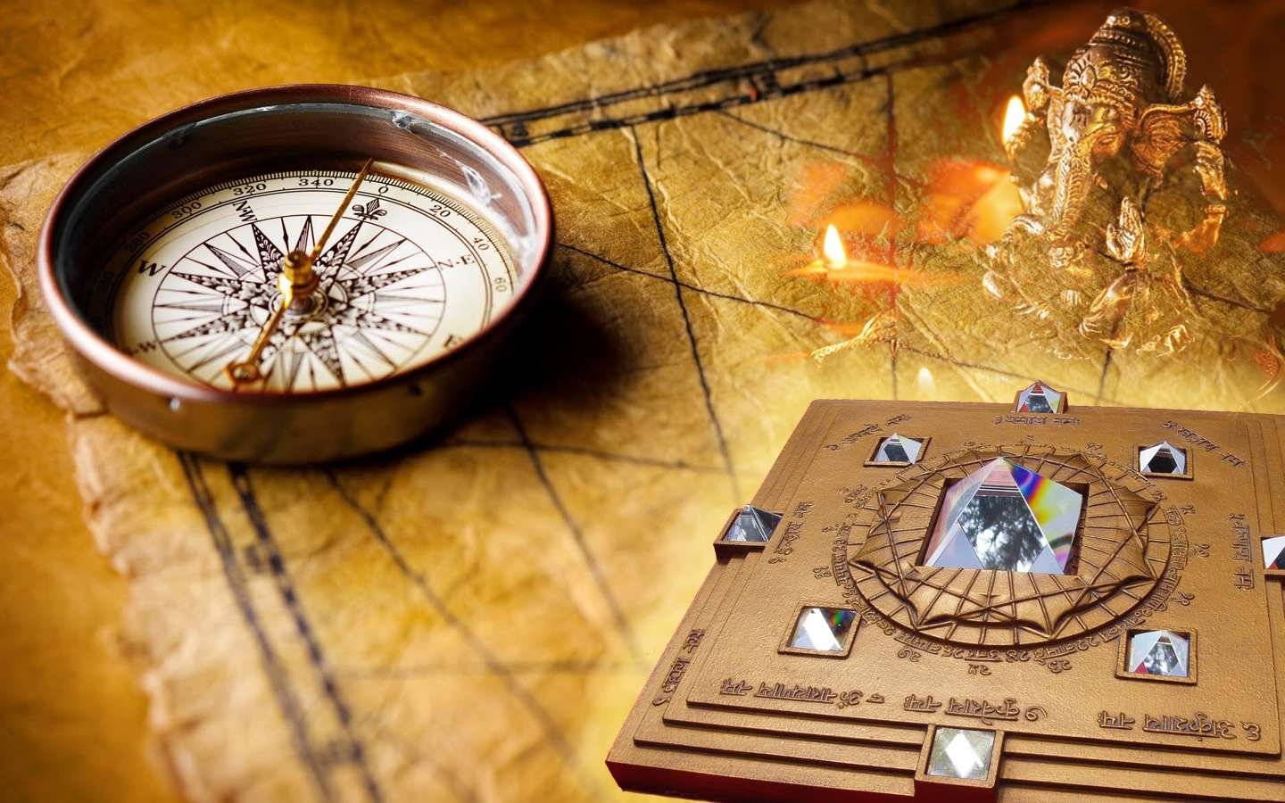 A traditional compass, a geometric yantra with crystals, and a statue of Lord Ganesha with oil lamps, all placed on an aged parchment or map.